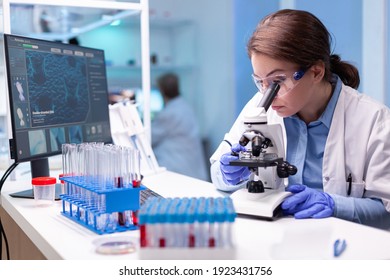 Scientist looking into microscope in virus research laboratory with pharmacy development equipment. Woman working on science vaccine chemistry experiment in modern lab, analyzing pharmaceutical work - Shutterstock ID 1923431756
