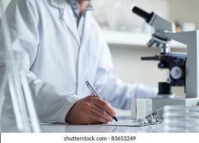 Scientist Making Notes Conducting Research Looking Through Microscope Selective Focus