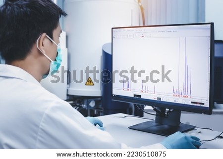 Scientist man checks the spectrum of sample analysis by nuclear magnetic resonance spectroscopy, NMR spectroscopy, as shown on a computer monitor in the laboratory.