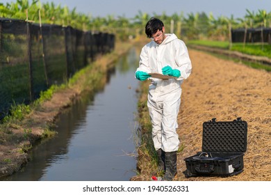 A Scientist Man In Full Body Protective Suit Collecting And Testing Water Quality In The Vegetable Farm