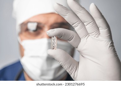 scientist man in goggles, gloves and mask holds DNA capsule, concept of scientific molecular biotechnology, study of human genetics, close-up - Powered by Shutterstock