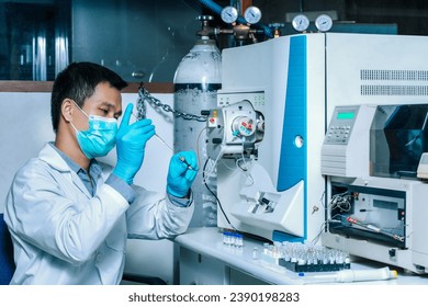 A scientist man injects a sample with a micro syringe into Mass Spectrometer to analyze samples, Mass spectrometry is used to measure mass per charge connected to Liquid Chromatography LC-MS