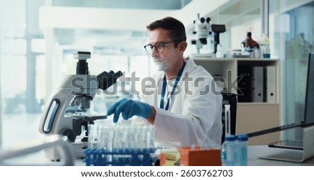 Scientist, man and sample by microscope in lab for medical research with container, test or vaccine development. Person, process and chemical analysis with pharma trial, drugs and petri dish by lens