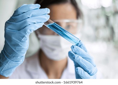 Scientist or medical in lab coat holding test tube with reagent, Laboratory glassware containing chemical liquid, Microscope, Biochemistry laboratory research. - Powered by Shutterstock