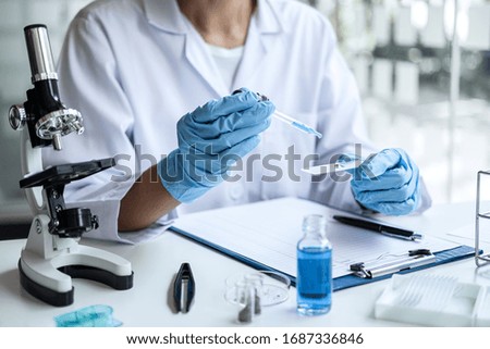 Scientist or medical in lab coat holding test tube with reagent, mixing reagents in glass flask, glassware containing chemical liquid, laboratory research and testing of Microscope.