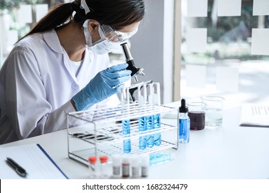 Wissenschaftler oder medizinischer Laborspezialist in biotechnologischem Labor, Mikroskop-Ausrüstung für die Forschung mit Mischreagenzien in Glaskolben im klinischen Labor.
