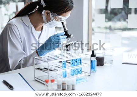 Scientist or medical in lab coat working in biotechnological laboratory, Microscope equipment for research with mixing reagents in glass flask in clinical laboratory.