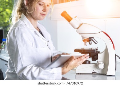 Scientist with microscope and tablet pc at the laboratory