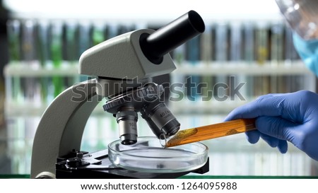 Scientist observing samples of oil spill under microscope to assess risks