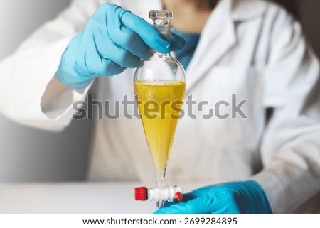 Scientist performing liquid–liquid extraction with separatory funnel in laboratory. Concept of natural product research, organic chemistry, and pharmaceutical formulation process.