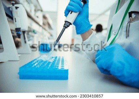 Scientist pipetting samples into tray in laboratory