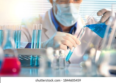 Scientist Pouring Blue Liquid From A Beaker Into A Test Tube Close Up. Horizontal Composition. Front View.