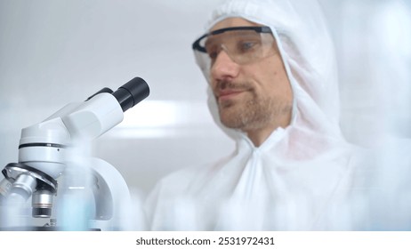 Scientist in ppe analyzing samples with microscope. Close-up of a focused researcher in a lab coat and protective gear using a microscope in a laboratory setting - Powered by Shutterstock