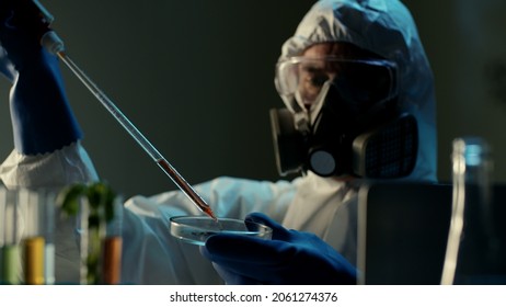 Scientist In Ppe Suit Analyzing Sample On Petri Dish Using Micropipette. Chemist In Coverall Working With Various Bacteria