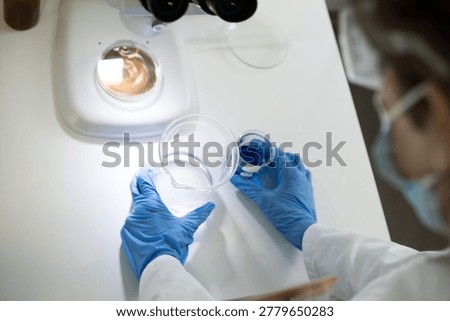 Scientist in protective gear preparing samples for microscopic examination, focusing on infectious disease study like Hantavirus.