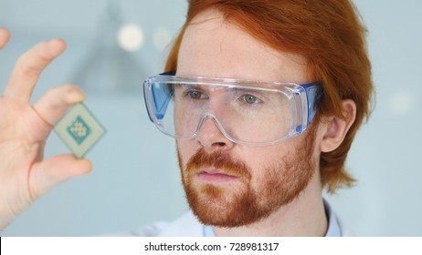 Scientist in Protective Glasses Looking at Computer Chip