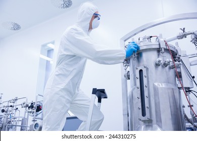 Scientist in protective suit standing on ladder in the factory - Powered by Shutterstock