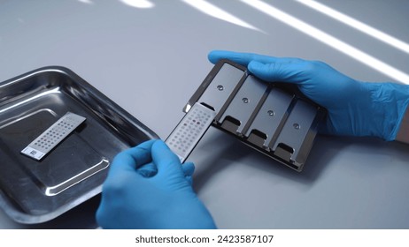 Scientist puts samples in microbiological analyzer in modern laboratory. Microbiologist does biotechnology or pharmaceutical research for antibiotics, develops drugs or vaccine in advanced lab.