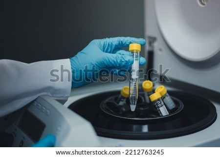 Scientist remove the test tubes of sample extraction from the centrifuge machine after centrifuging for DNA research into the next step.