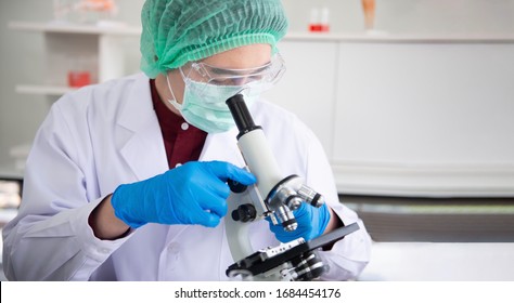 Scientist researcher using the microscope in Laboratory. Man scientist looking through a microscope in Laboratory.