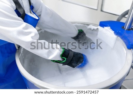 Scientist Retrieving Samples from Cryogenic Storage Tank. A researcher wearing full protective gear, including insulated gloves and a safety apron, carefully reaches into a nitrogen storage tank.