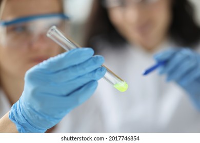 Scientist shows test tube with yellow substance in laboratory