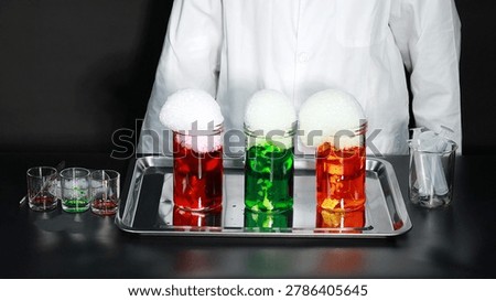 A scientist stands behind three jars of colored liquid overflowing with thick white foam.