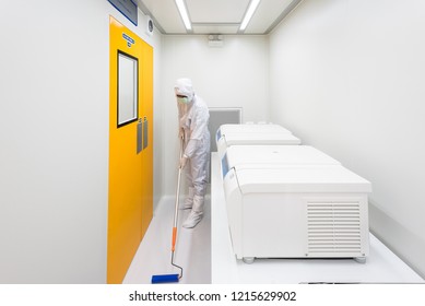 A Scientist In Sterile Coverall Gown Using Lint Roller For Cleaning Laboratory. Cleanroom Facility.
