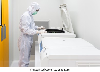 A Scientist In Sterile Coverall Gown Using Laboratory Equipment For Doing Biological Research In Cleanroom. 