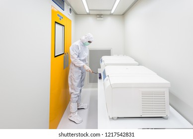 A Scientist In Sterile Coverall Gown Using Lint Roller For Cleaning Laboratory. Cleanroom Facility.
