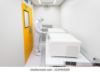 A Scientist In Sterile Coverall Gown Using Laboratory Equipment For Doing Biological Research In Cleanroom. 