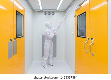 A Scientist In Sterile Coverall Gown Using Cleaning Tool For Cleaning Laboratory. Cleanroom Facility.