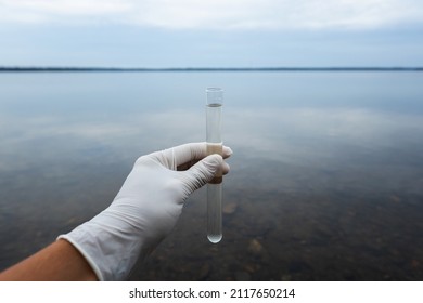  The Scientist Is Taking Water Sample Of Sea Water. Test Tube With Water In A Hand. Sea Water Pollution Concept. Cloudy Sky.



