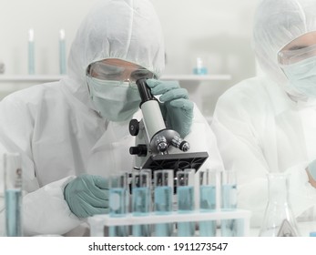 Scientist Team Wears Protective Clothing Working In Research Laboratory. Asian Male Doctor Researcher Wear Protective Glasses Diagnosis Blood Test Covid Vaccine Via Microscope In Health Care Business