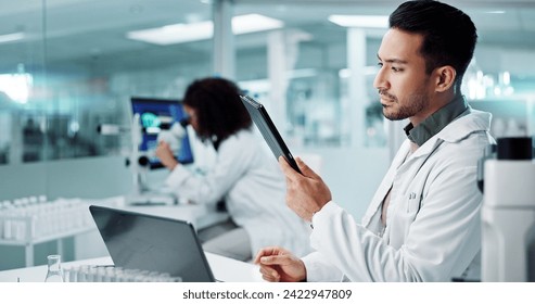 Scientist, thinking on computer and tablet for laboratory research, DNA analysis and results in medical study at night. Young man of science and biotechnology, digital software or laptop for solution
