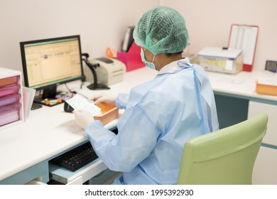 Scientist typing a report with his computer.Lab assistant recording results of science experiment in chemical laboratory unit. Coronavirus (COVID-19) investigations concept.