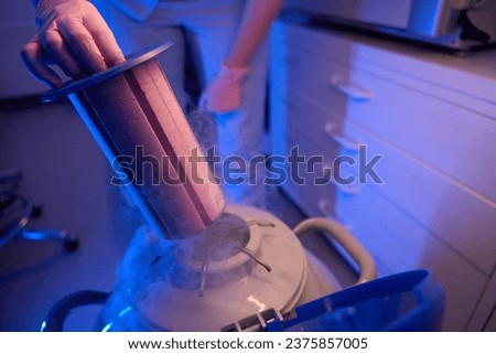 Scientist using cryogenic tank for preservation of biological samples