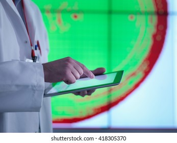 Scientist using digital tablet in front of graphical display of silicon wafer on screens, close up