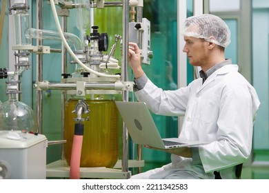 scientist using laptop computer for operating machine in cannabis testing lab