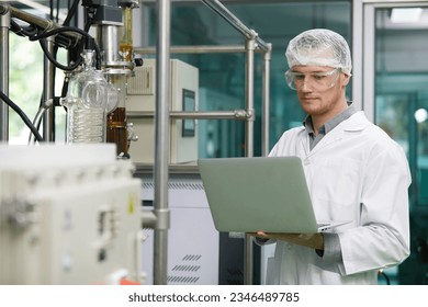 scientist using laptop computer for operating machine in cannabis testing lab