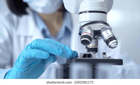 Scientist using microscope in laboratory. Close-up of a researcher's hands adjusting a modern microscope in a lab setting. Science concept
