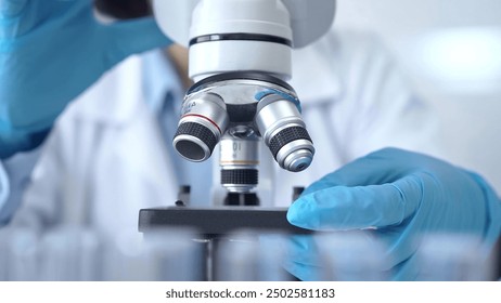 Scientist using microscope in laboratory. Close-up of a researcher's hands adjusting a modern microscope in a lab setting