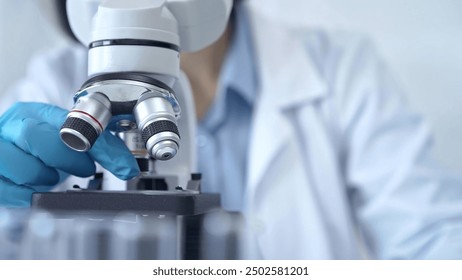 Scientist using microscope in laboratory. Close-up of a researcher's hands adjusting a modern microscope in a lab setting. Science concept