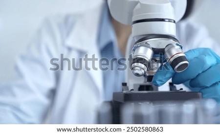 Scientist using microscope in laboratory. Close-up of a researcher's hands adjusting a modern microscope in a lab setting. Science concept