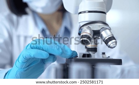 Scientist using microscope in laboratory. Close-up of a researcher's hands adjusting a modern microscope in a lab setting. Science concept