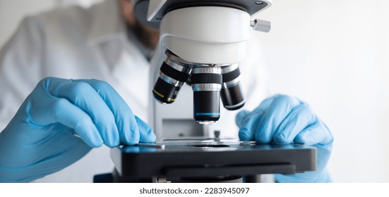Scientist using microscope in laboratory, making medical testing and research, close-up
