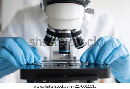 Scientist using microscope in laboratory, making medical testing and research, close-up