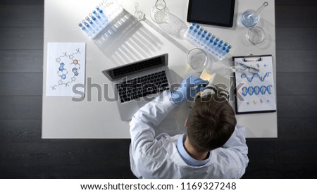 Scientist viewing samples under microscope, research for scientific article
