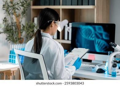Scientist wearing lab coat and gloves analyzing dna structure on computer screen and checking data on clipboard in modern laboratory