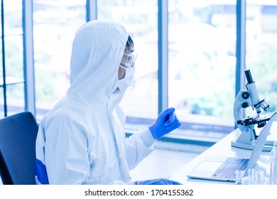 A Scientist Wearing Protective Mask, Glasses And Jumpsuit With Blue Gloves Worked In Laboratory 